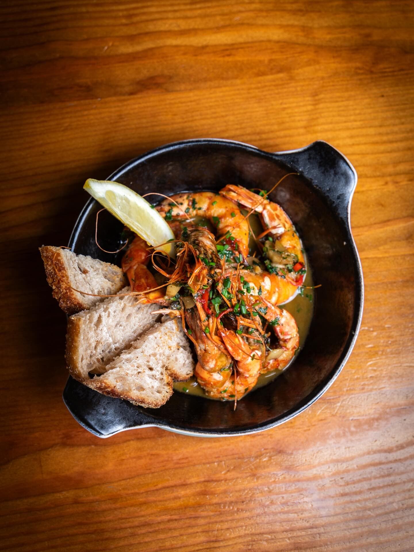 Garlic prawns with bread on an oak table